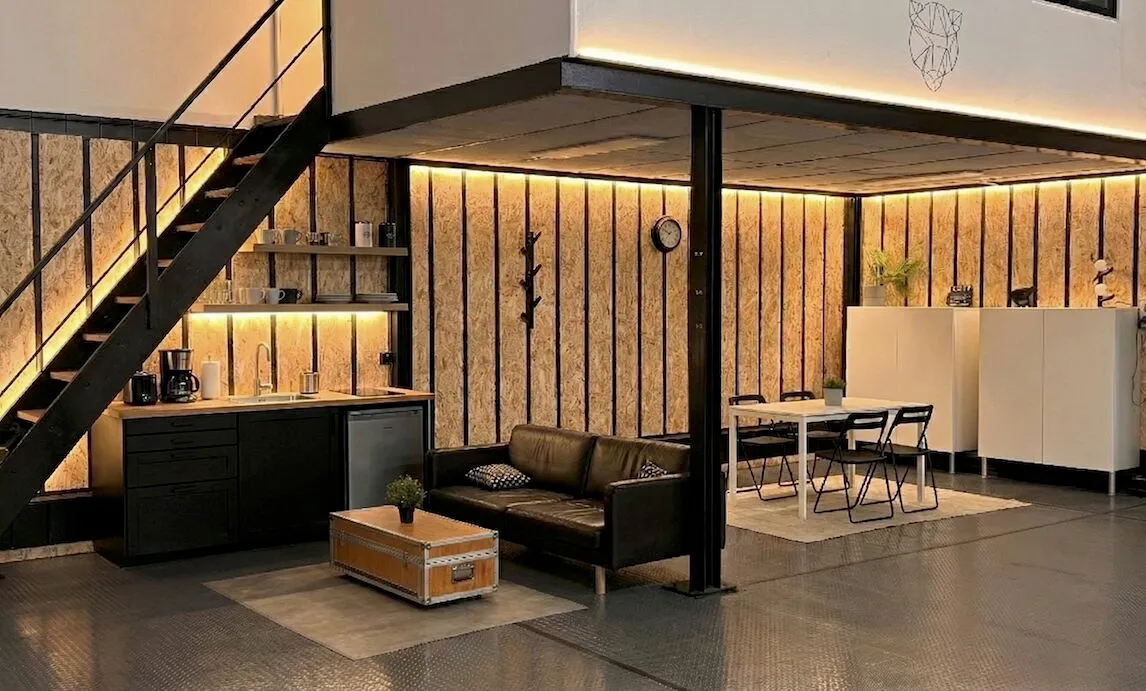 Zona de descanso del plató de On White en Sevilla: cocina, sofá y mesa bajo el altillo